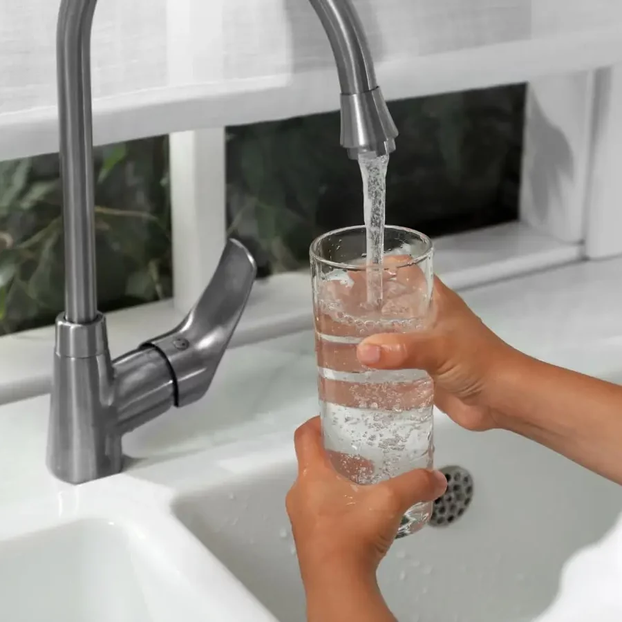 Cumberland Plateau Water Authority In a kitchen, a child carefully holds a glass while standing by the sink as the water fills the glass.